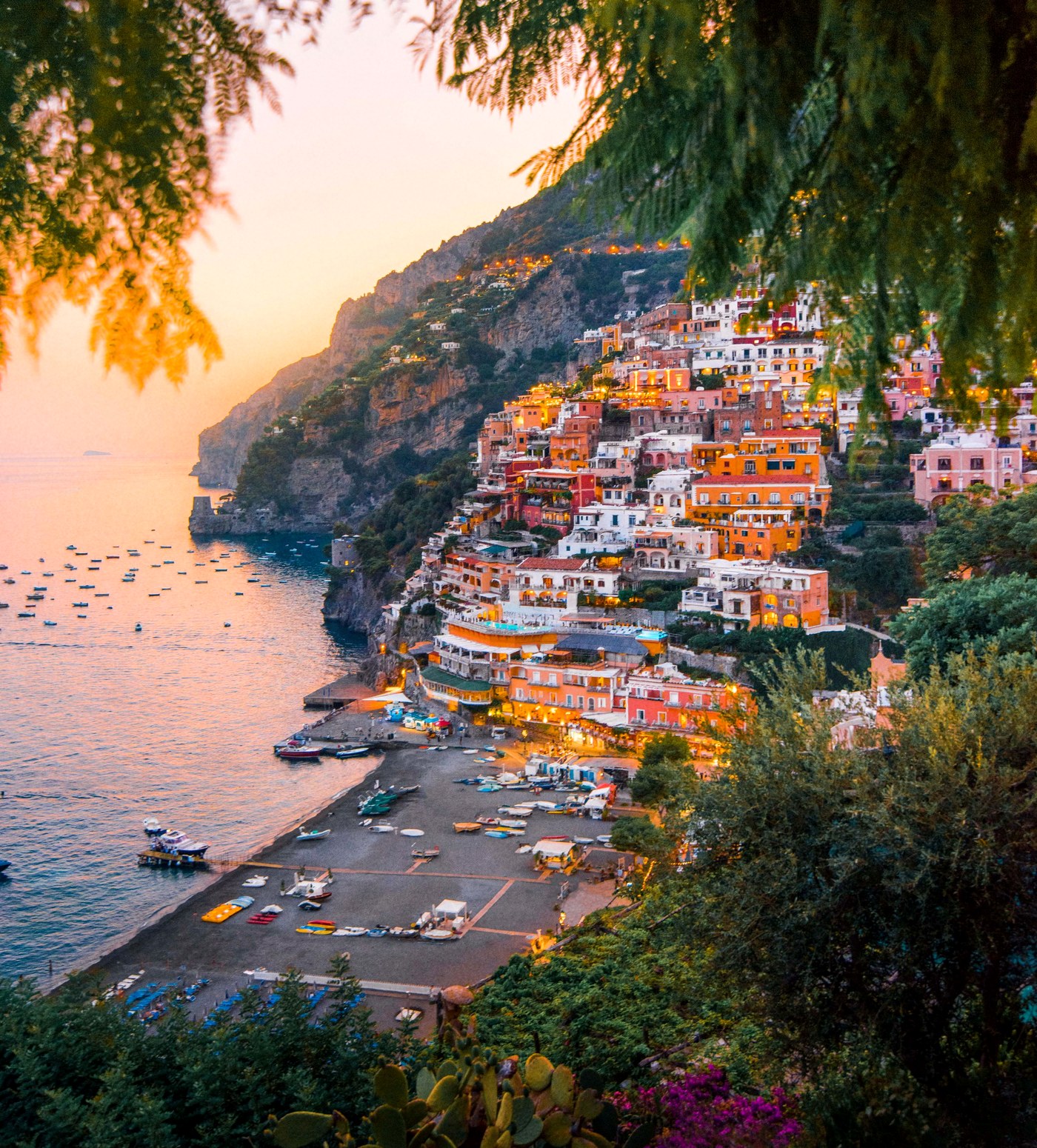 Positano on the Amalfi Coast at sunset, cliffside houses glowing above the sea